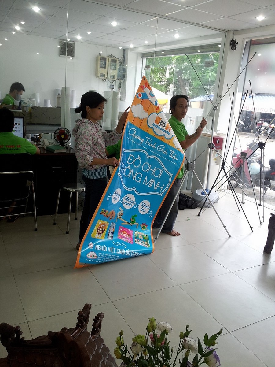 Nhân viên DVQuangCao đang tiến hành hướng dẫn khách hàng lắp đặt poster PP vào kệ standee